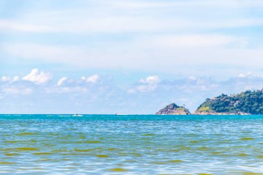 Patong Beach bay sea coast panorama view with turquoise blue clear water waves white sand and green mountains and palm trees in Patong Beach Kathu District Phuket Island Province Southern Thailand.