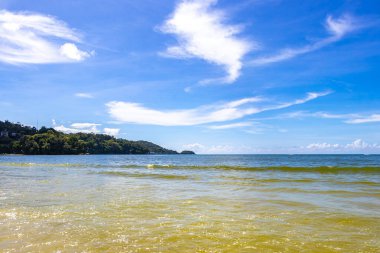 Patong Beach bay sea coast panorama view with turquoise blue clear water waves white sand and green mountains and palm trees in Patong Beach Kathu District Phuket Island Province Southern Thailand.