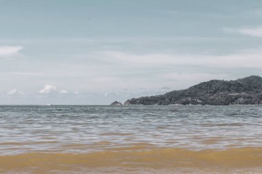 Patong Beach bay sea coast panorama view with turquoise blue clear water waves white sand and green mountains and palm trees in Patong Beach Kathu District Phuket Island Province Southern Thailand.