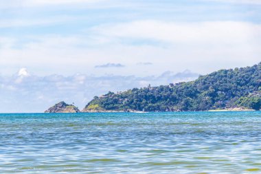 Patong Beach bay sea coast panorama view with turquoise blue clear water waves white sand and green mountains and palm trees in Patong Beach Kathu District Phuket Island Province Southern Thailand.