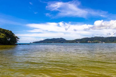 Patong Beach bay sea coast panorama view with turquoise blue clear water waves white sand and green mountains and palm trees in Patong Beach Kathu District Phuket Island Province Southern Thailand.