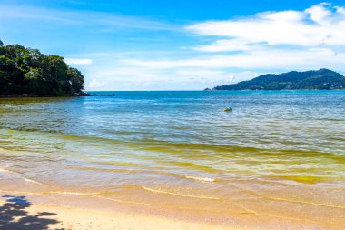 Patong Beach bay sea coast panorama view with turquoise blue clear water waves white sand and green mountains and palm trees in Patong Beach Kathu District Phuket Island Province Southern Thailand.