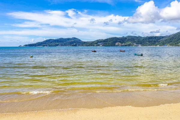 Patong Beach bay sea coast panorama view with turquoise blue clear water waves white sand and green mountains and palm trees in Patong Beach Kathu District Phuket Island Province Southern Thailand.