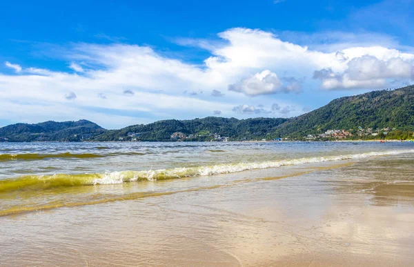 Patong Beach bay sea coast panorama view with turquoise blue clear water waves white sand and green mountains and palm trees in Patong Beach Kathu District Phuket Island Province Southern Thailand.