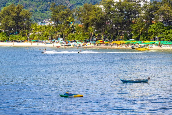 Kathu Phuket Tayland 13 numara. Ekim 2025 Patong Sahili manzaralı gezinti turistleri mavi su dalgaları güneş şemsiyeleri cankurtaran kuleleri dağlar ve Tayland palmiyeleri.