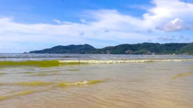 Patong Beach bay sea coast panorama view with turquoise blue clear water waves white sand and green mountains and palm trees in Patong Beach Kathu District Phuket Island Province Southern Thailand.