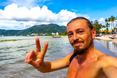 Güneydoğu Asya 'da Patong Sahili' nde turkuaz mavi su ve beyaz kumla gezen yakışıklı turist Kathu Bölgesi Phuket Adası Bölgesi Güney Tayland.