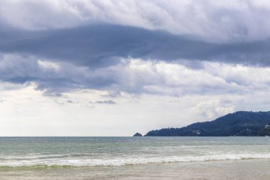 Patong Sahili sahil sahili panorama manzarası turkuaz mavi berrak su dalgaları ve yeşil tepeler ve Patong Sahili 'ndeki palmiye ağaçları Kathu Bölgesi Phuket Adası Güney Tayland.