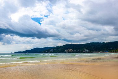 Patong Beach bay sea coast panorama view with turquoise blue clear water waves white sand and green mountains and palm trees in Patong Beach Kathu District Phuket Island Province Southern Thailand.