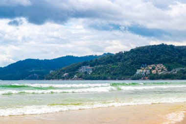 Patong Beach bay sea coast panorama view with turquoise blue clear water waves white sand and green mountains and palm trees in Patong Beach Kathu District Phuket Island Province Southern Thailand.