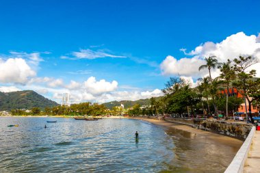 Kathu Phuket Thailand 13. October 2025 Patong Beach bay sea coast panorama view with promenade tourists people turquoise blue water boats mountains and palm trees in Patong Phuket Thailand.