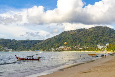 Kathu Phuket Thailand 13. October 2025 Patong Beach bay sea coast panorama view with promenade tourists people turquoise blue water boats mountains and palm trees in Patong Phuket Thailand.