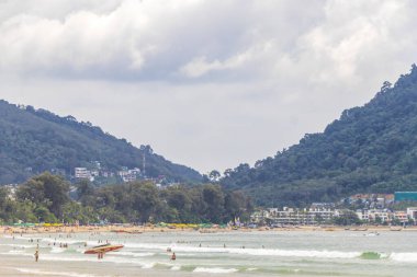 Kathu Phuket Tayland 17 numara. Ekim 2025 Patong Sahili sahil manzaralı gezinti turistleri açık mavi su dalgaları ve yeşil dağlar ve Patong Tayland 'daki palmiye ağaçları..
