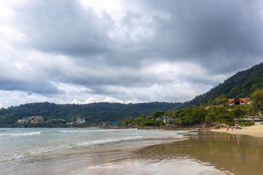 Kathu Phuket Tayland 17 numara. Ekim 2025 Patong Sahili sahil manzaralı gezinti turistleri açık mavi su dalgaları ve yeşil dağlar ve Patong Tayland 'daki palmiye ağaçları..
