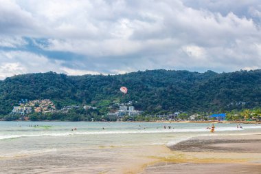Kathu Phuket Tayland 17 numara. Ekim 2025 Patong Sahili sahil manzaralı gezinti turistleri açık mavi su dalgaları ve yeşil dağlar ve Patong Tayland 'daki palmiye ağaçları..
