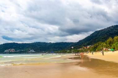 Kathu Phuket Tayland 17 numara. Ekim 2025 Patong Sahili sahil manzaralı gezinti turistleri açık mavi su dalgaları ve yeşil dağlar ve Patong Tayland 'daki palmiye ağaçları..