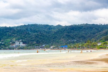 Patong Beach bay sea coast panorama view with turquoise blue clear water waves white sand and green mountains and palm trees in Patong Beach Kathu District Phuket Island Province Southern Thailand.
