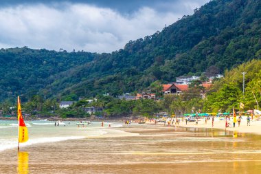 Kathu Phuket Tayland 17 numara. Ekim 2025 Patong Sahili sahil manzaralı gezinti turistleri açık mavi su dalgaları ve yeşil dağlar ve Patong Tayland 'daki palmiye ağaçları..