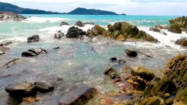 İnanılmaz kayalık Kalim Sahili tropikal manzara manzarası mavi gökyüzü turkuvaz su dalgaları ve kayalar ile Patong Sahili Kathu Bölgesi Phuket Adası Güney Tayland.