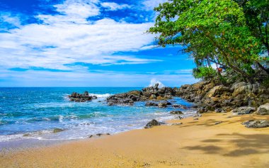 İnanılmaz kayalık Kalim Sahili tropikal manzara manzarası mavi gökyüzü turkuvaz su dalgaları palmiye ağaçları ve kayalar Patong Sahili Kathu Phuket Adası Güney Tayland.