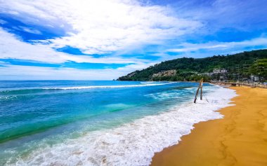Kalim Sahili sahili deniz manzarası turkuvaz mavisi berrak su dalgaları beyaz kum ve yeşil dağlar ve Patong Sahili 'ndeki palmiye ağaçları Kathu Phuket Adası Güney Tayland.