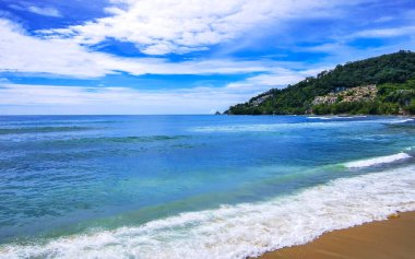 Kalim Sahili sahili deniz manzarası turkuvaz mavisi berrak su dalgaları beyaz kum ve yeşil dağlar ve Patong Sahili 'ndeki palmiye ağaçları Kathu Phuket Adası Güney Tayland.