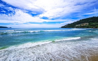 Kalim Sahili sahili deniz manzarası turkuvaz mavisi berrak su dalgaları beyaz kum ve yeşil dağlar ve Patong Sahili 'ndeki palmiye ağaçları Kathu Phuket Adası Güney Tayland.