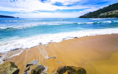 İnanılmaz kayalık Kalim Sahili tropikal manzara manzarası mavi gökyüzü turkuvaz su dalgaları ve kayalar ile Patong Sahili Kathu Bölgesi Phuket Adası Güney Tayland.