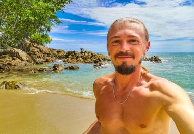 Güneydoğu Asya 'daki Güney Tayland' da Patong Sahili Kathu Bölgesi Phuket Adası Eyaleti 'nde turkuaz mavi su kayaları ve beyaz kumla tropik Kalim Sahili' nde seksi yakışıklı turist..