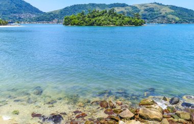 Rio de Janeiro Brezilya 'nın Angra dos Reis eyaletinde turkuvaz yeşili ve berrak su kayaları ve mavi gökyüzü ile tropik adalar adası sahili manzarası..
