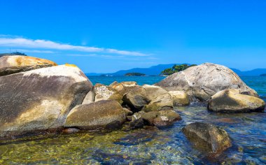 Turkuvaz yeşili ve berrak su kayaları, kaya kayaları ve mavi gökyüzü ile tropik adalar adası sahili manzarası Rio de Janeiro Brezilya 'nın Reis eyaletinde..