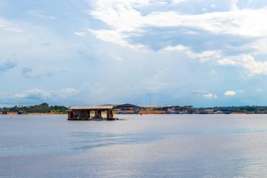 Amazon Eyaleti Amazon Manaus Brezilya 'da Amazon Nehri kıyısındaki Rio Negro' nun kara sularında tropikal yağmur ormanlarında ve mavi bulutlu gökyüzünde köy kulübelerinde ve kulübelerde evler..