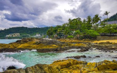 İnanılmaz kayalık Kalim Sahili tropikal manzara manzarası mavi gökyüzü turkuvaz su dalgaları palmiye ağaçları ve kayalar Patong Sahili Kathu Phuket Adası Güney Tayland.