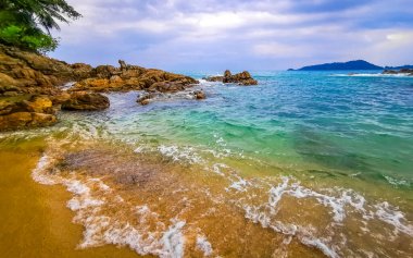İnanılmaz kayalık Kalim Sahili tropikal manzara manzarası mavi gökyüzü turkuvaz su dalgaları palmiye ağaçları ve kayalar Patong Sahili Kathu Phuket Adası Güney Tayland.