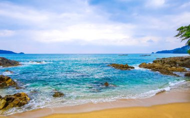 İnanılmaz kayalık Kalim Sahili tropikal manzara manzarası mavi gökyüzü turkuvaz su dalgaları palmiye ağaçları ve kayalar Patong Sahili Kathu Phuket Adası Güney Tayland.