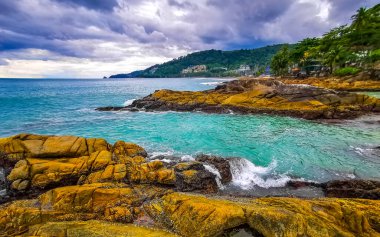 İnanılmaz kayalık Kalim Sahili tropikal manzara manzarası mavi gökyüzü turkuvaz su dalgaları palmiye ağaçları ve kayalar Patong Sahili Kathu Phuket Adası Güney Tayland.