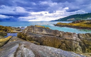İnanılmaz kayalık Kalim Sahili tropikal manzara manzarası mavi gökyüzü turkuvaz su dalgaları ve kayalar ile Patong Sahili Kathu Bölgesi Phuket Adası Güney Tayland.