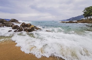 İnanılmaz kayalık Kalim Sahili tropikal manzara manzarası mavi gökyüzü turkuvaz su dalgaları ve kayalar ile Patong Sahili Kathu Bölgesi Phuket Adası Güney Tayland.