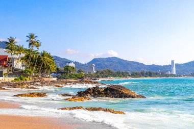 İnanılmaz kayalık Kalim Sahili tropikal manzara manzarası mavi gökyüzü turkuvaz su dalgaları palmiye ağaçları ve kayalar Patong Sahili Kathu Phuket Adası Güney Tayland.