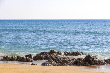 Rocky Kalim Plajı tropikal manzara manzarası turkuvaz mavisi temiz su dalgaları ile Patong Sahili 'nde Kathu Bölgesi Phuket Adası Güney Tayland' da kum ve kayalar.