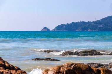 Rocky Kalim Plajı tropikal manzara manzarası turkuvaz mavisi temiz su dalgaları ile Patong Sahili 'nde Kathu Bölgesi Phuket Adası Güney Tayland' da kum ve kayalar.