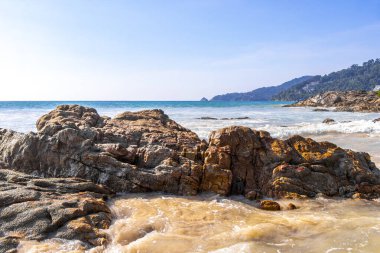 Rocky Kalim Plajı tropikal manzara manzarası turkuvaz mavisi temiz su dalgaları ile Patong Sahili 'nde Kathu Bölgesi Phuket Adası Güney Tayland' da kum ve kayalar.