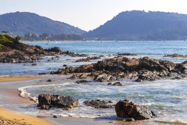 Rocky Kalim Plajı tropikal manzara manzarası turkuvaz mavisi temiz su dalgaları ile Patong Sahili 'nde Kathu Bölgesi Phuket Adası Güney Tayland' da kum ve kayalar.