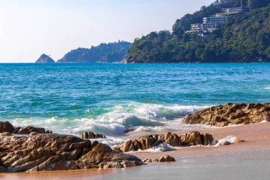Rocky Kalim Plajı tropikal manzara manzarası turkuvaz mavisi temiz su dalgaları ile Patong Sahili 'nde Kathu Bölgesi Phuket Adası Güney Tayland' da kum ve kayalar.