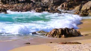 Rocky Kalim Plajı tropikal manzara manzarası turkuvaz mavisi temiz su dalgaları ile Patong Sahili 'nde Kathu Bölgesi Phuket Adası Güney Tayland' da kum ve kayalar.