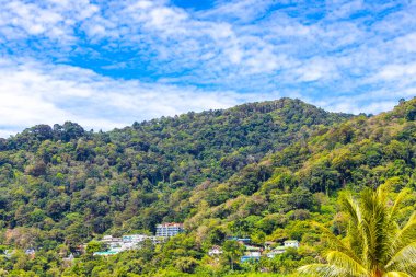 Tropical mountain with jungle forest trees plants clouds and blue sky in Patong Beach Kathu District Phuket Island Province Southern Thailand in Southeast Asia.
