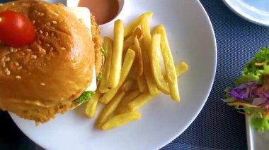 Patong Sahili 'ndeki Kathu Bölgesi Phuket Adası Tayland Eyaleti' nde bir restoranda salata ve patates kızartması ile kızarmış tavuk veya sığır burger çizburger..