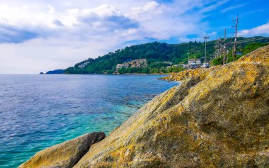 İnanılmaz kayalık Kalim Sahili tropikal manzara manzarası mavi gökyüzü turkuvaz su dalgaları palmiye ağaçları ve kayalar Patong Sahili Kathu Phuket Adası Güney Tayland.