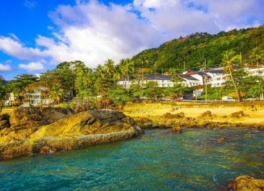 İnanılmaz kayalık Kalim Sahili tropikal manzara manzarası mavi gökyüzü turkuvaz su dalgaları palmiye ağaçları ve kayalar Patong Sahili Kathu Phuket Adası Güney Tayland.