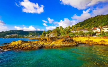 İnanılmaz kayalık Kalim Sahili tropikal manzara manzarası mavi gökyüzü turkuvaz su dalgaları palmiye ağaçları ve kayalar Patong Sahili Kathu Phuket Adası Güney Tayland.